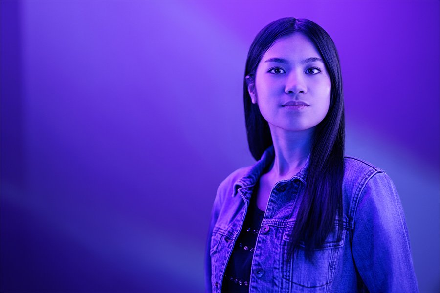 A person in a purple light looks off into the distance.